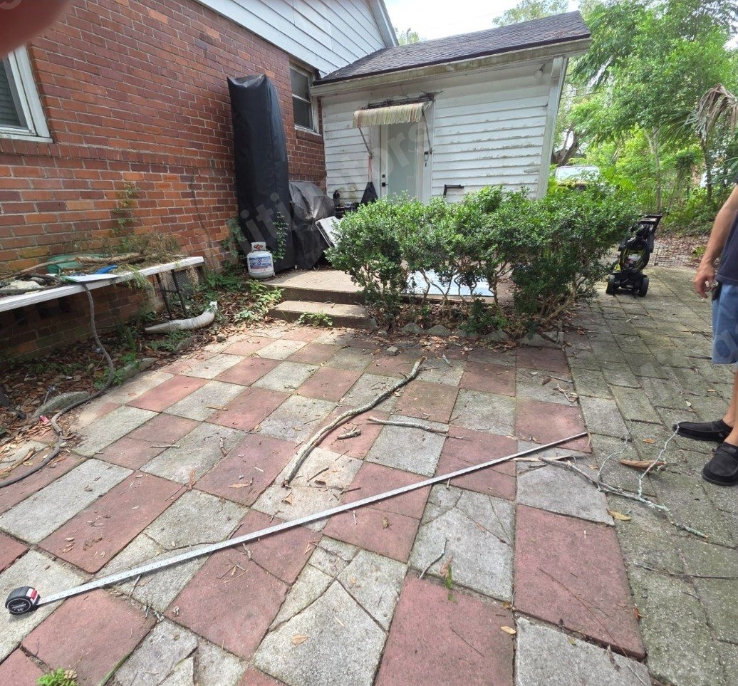 Deck project before — Overgrown paver patio transformed into a full covered deck with a metal roof — Jacksonville FL by P1Mitigators