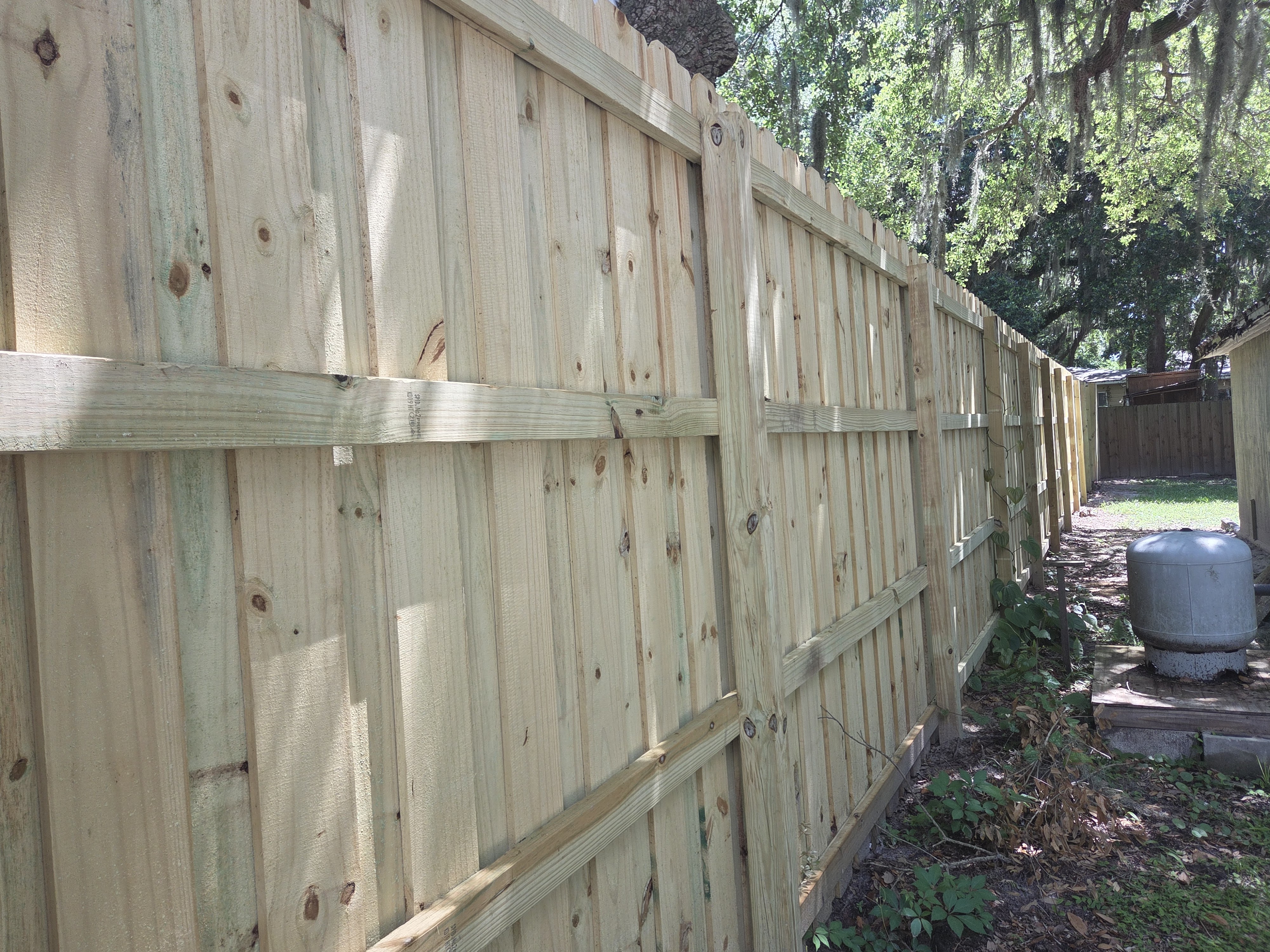 8-foot board on board fence back side detail — three-rail horizontal runners with propane tank Jacksonville FL