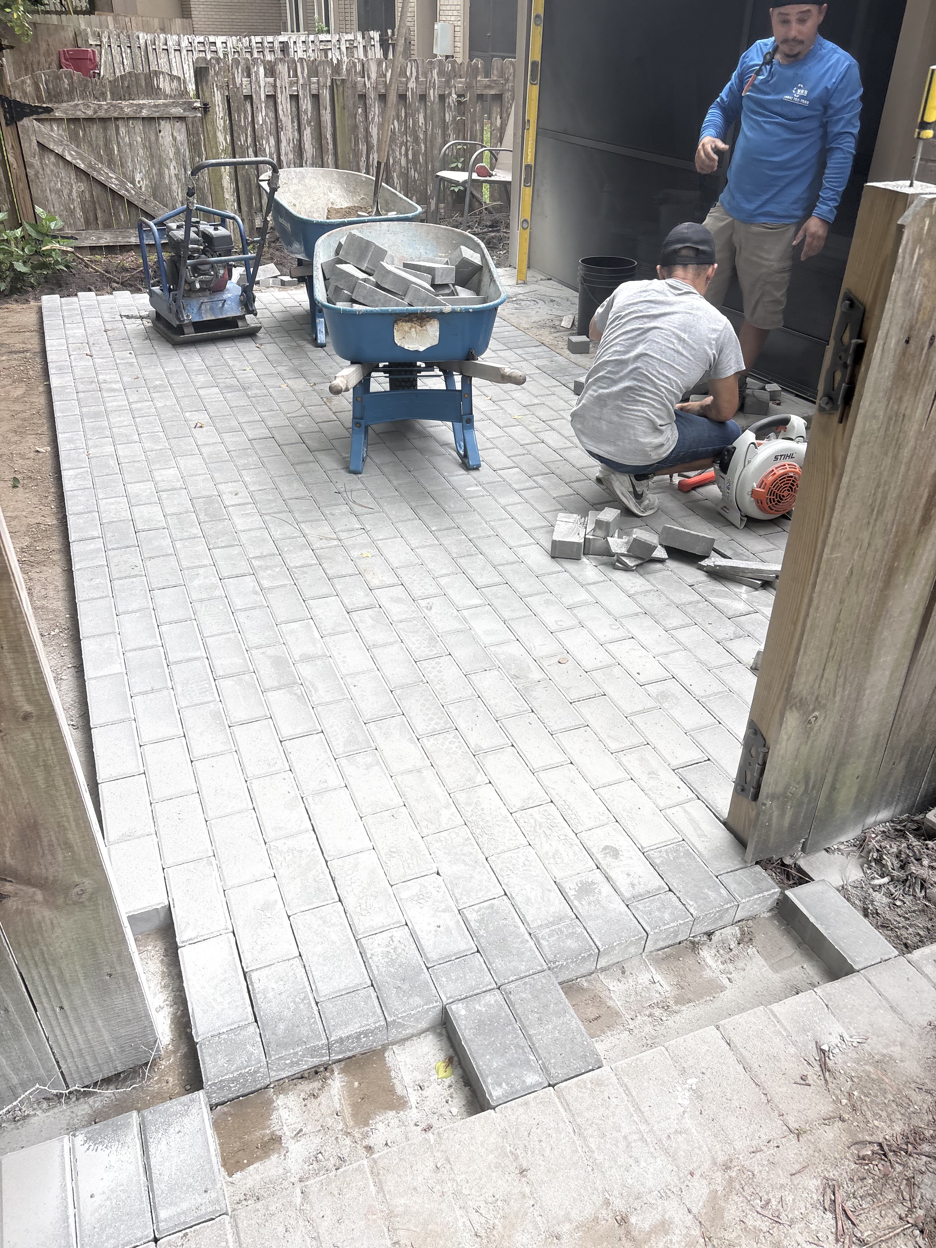 Crew installing brick paver driveway — cutting pavers on site