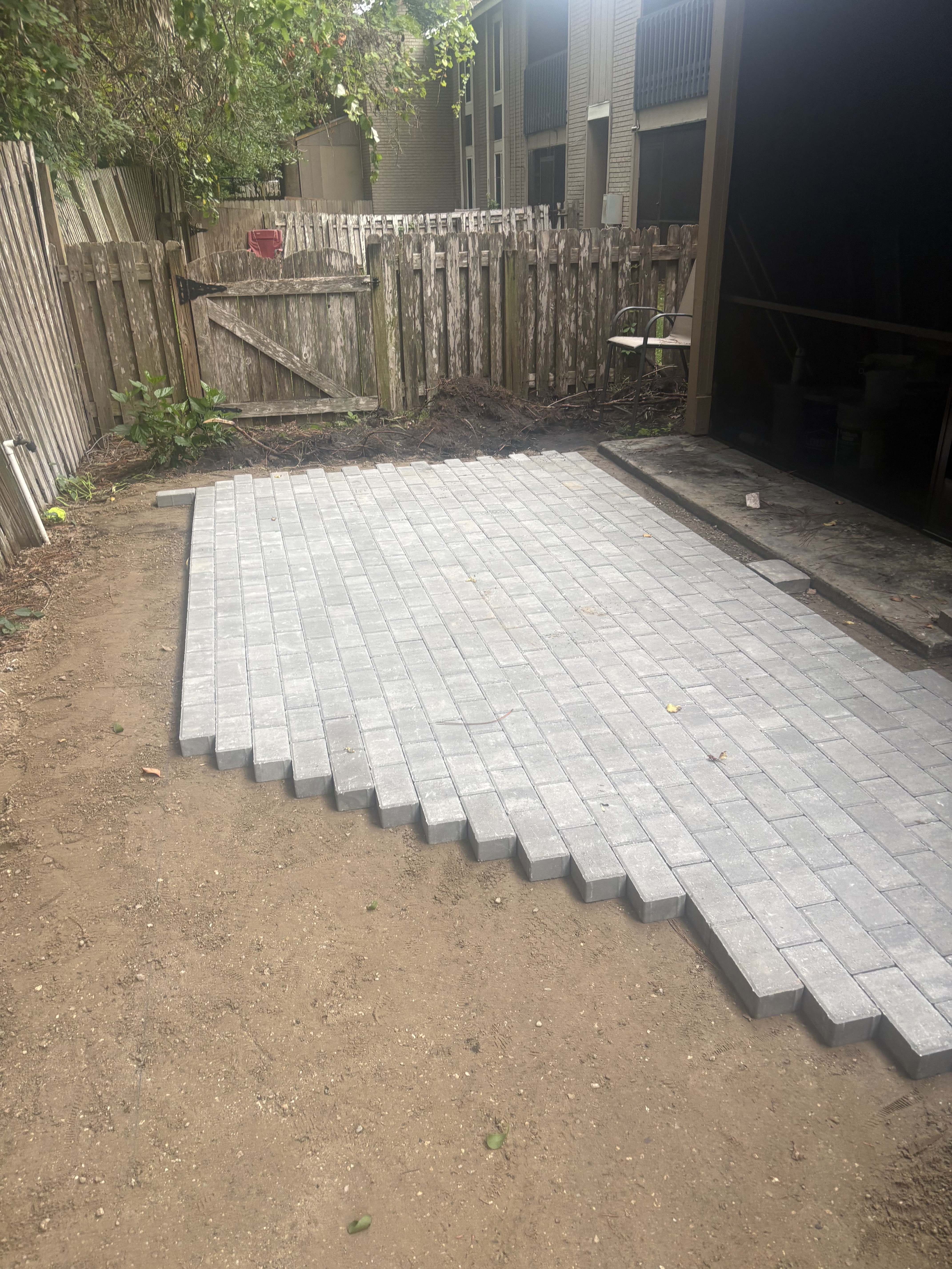 Paver driveway installation in progress — running bond pattern near garage