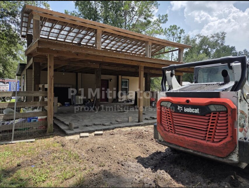 Bobcat skid steer under covered structure — pavers being laid