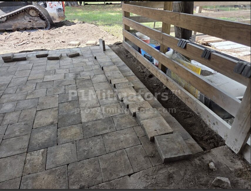 Close-up of finished paver pattern with border cuts along fence